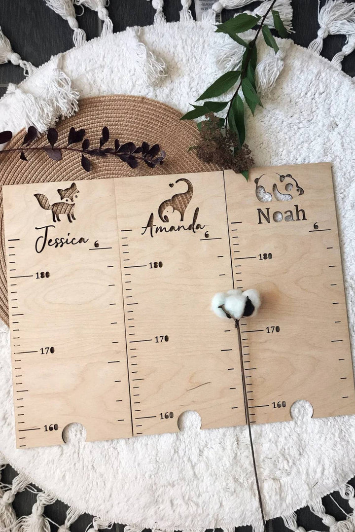 Personalized wooden growth chart ruler with engraved animal patterns for kids, featuring names Jessica, Amanda, and Noah.