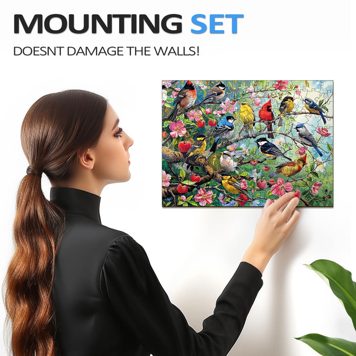 Woman hangs the Birds in the Orchard wooden jigsaw puzzle with a mounting set, showcasing the vibrant bird and flower design.