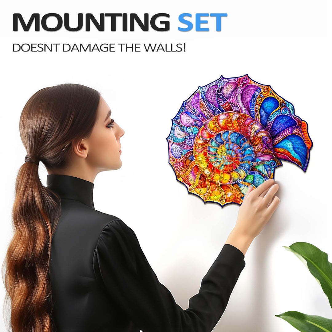 Woman mounting a colorful nautilus puzzle on the wall using a damage-free set, showcasing vibrant artwork.