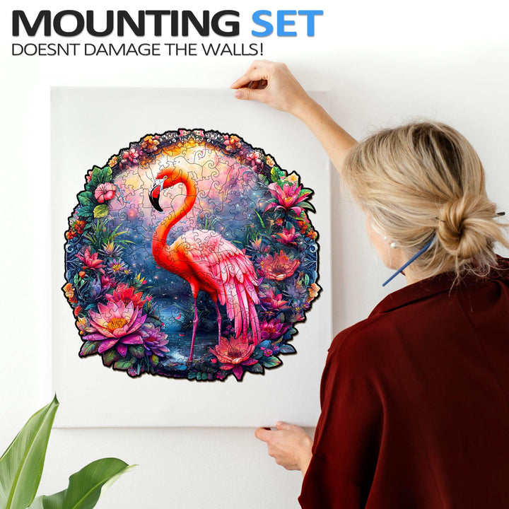Person mounting a colorful Elegant Flamingo jigsaw puzzle framed on the wall, showcasing vibrant art and involved puzzle solving.