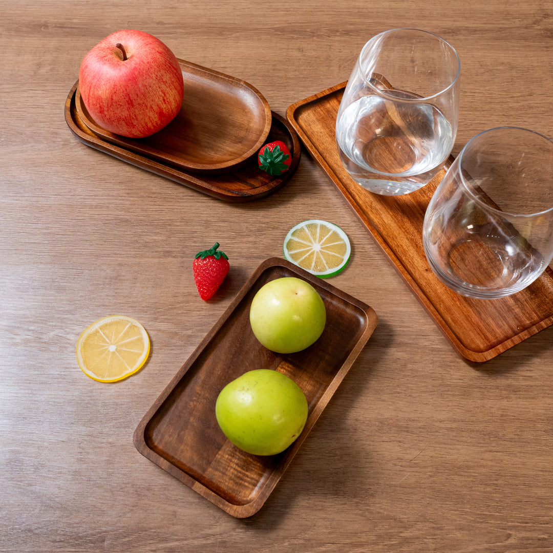 Organic wooden trays with fruits and glasses, showcasing eco-friendly acacia wood design for home decor.