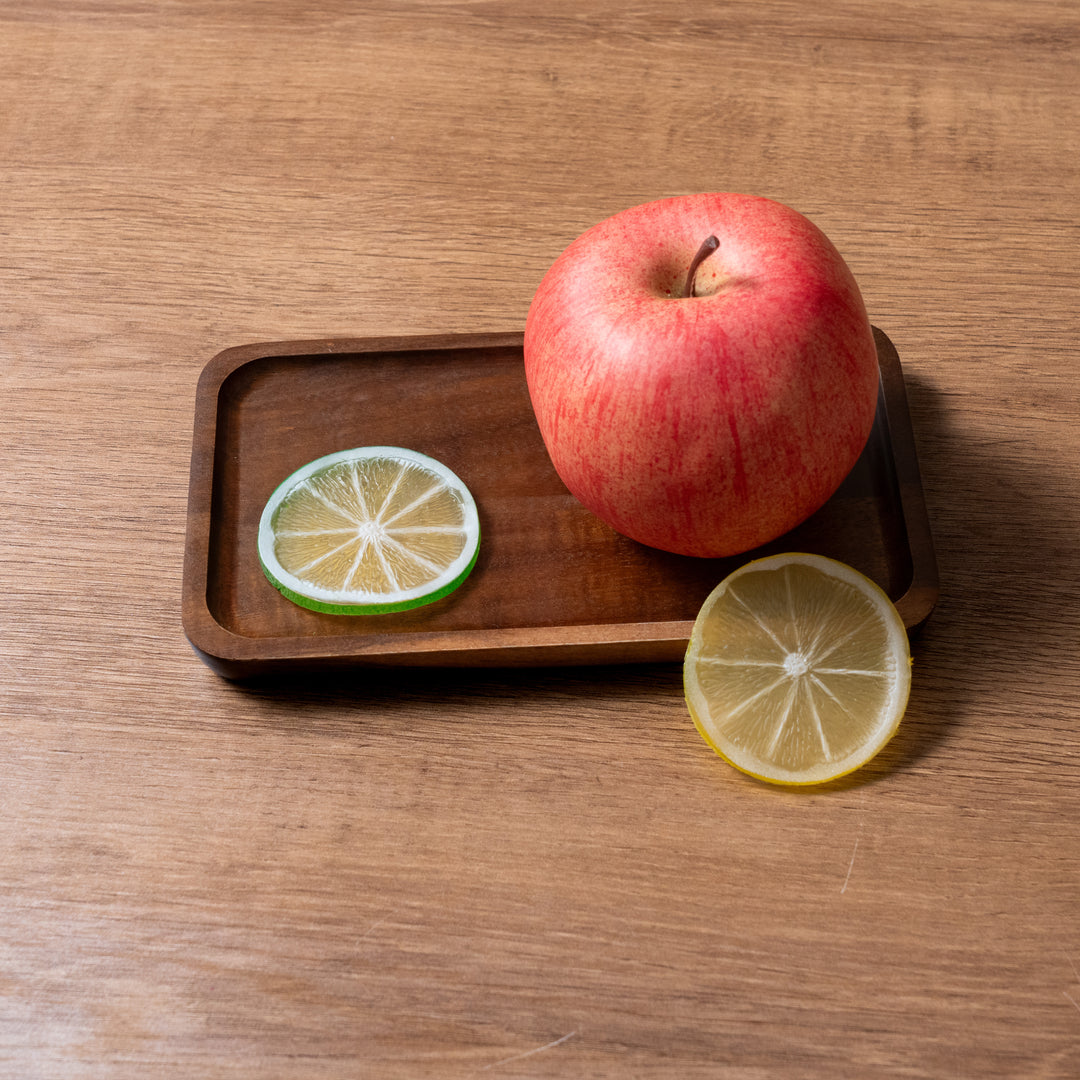 Acacia wood tray with an apple and lemon slices, showcasing organic wooden aesthetics and natural texture.