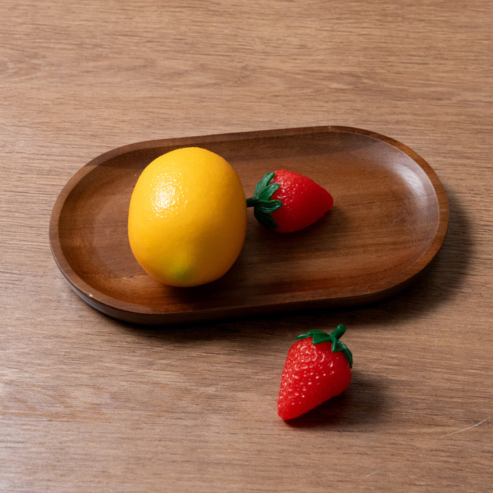 Organic acacia wood tray holding a lemon and two strawberries, showcasing natural beauty and practical design.