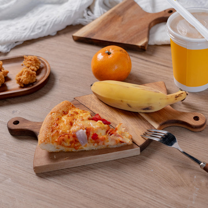 Delicious pizza slice on an acacia wood serving tray, with fruits and a drink, perfect for sharing meals.