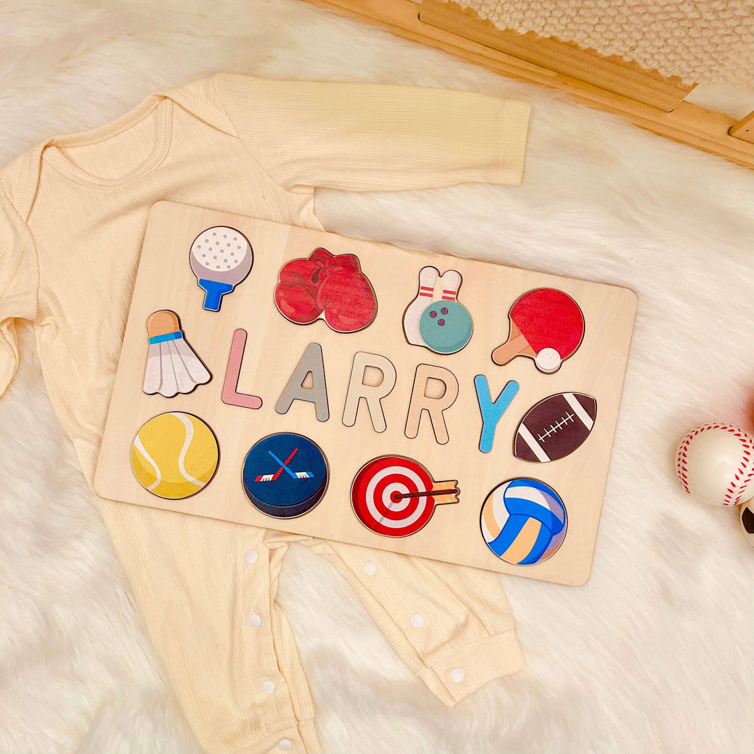 Personalized wooden baby name puzzle 'LARRY' with sports-themed icons on a cozy baby outfit background.