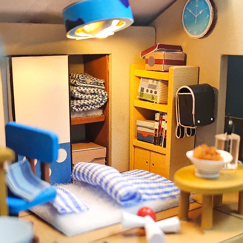 Interior view of a DIY Japanese-style dollhouse kit, showcasing cozy bedroom with bedding, shelves, and decor.