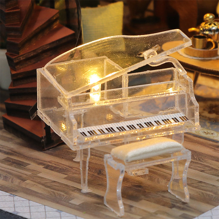 Clear miniature piano and bench in a DIY dollhouse, featuring a detailed keyboard and warm lighting.