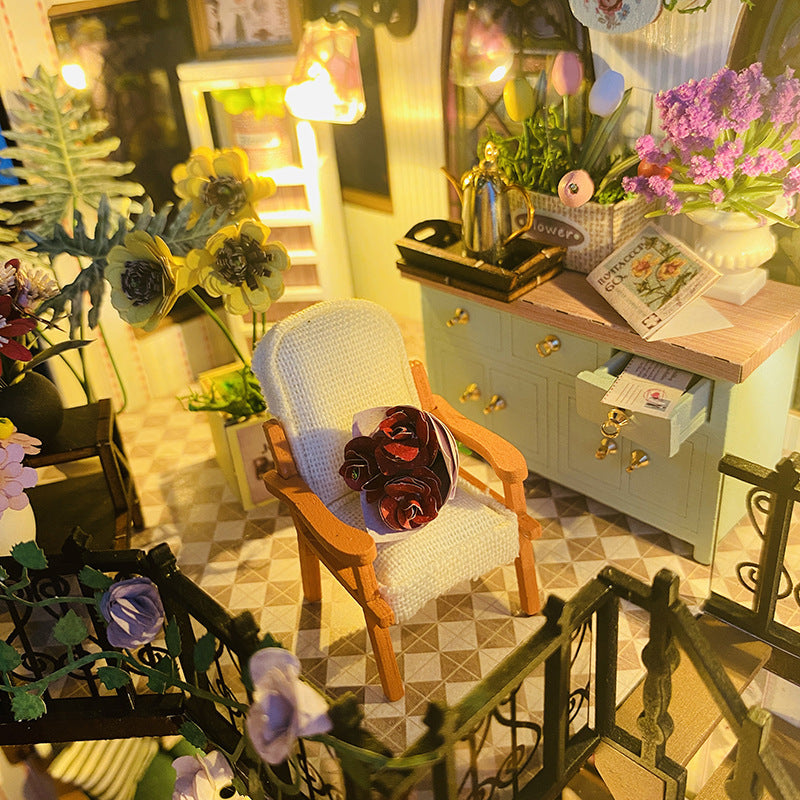 Cozy interior of Daisy's Flower Room dollhouse kit showcasing a chair, flowers, and decorative kitchen items.