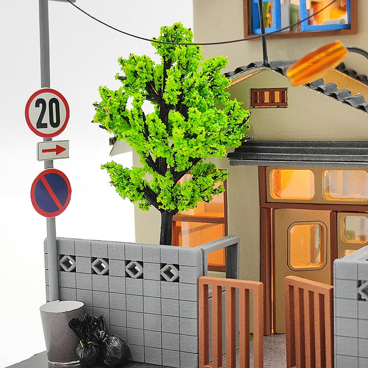 Miniature Japanese-style house with tree and street signs, part of a DIY dollhouse kit for creative assembly.