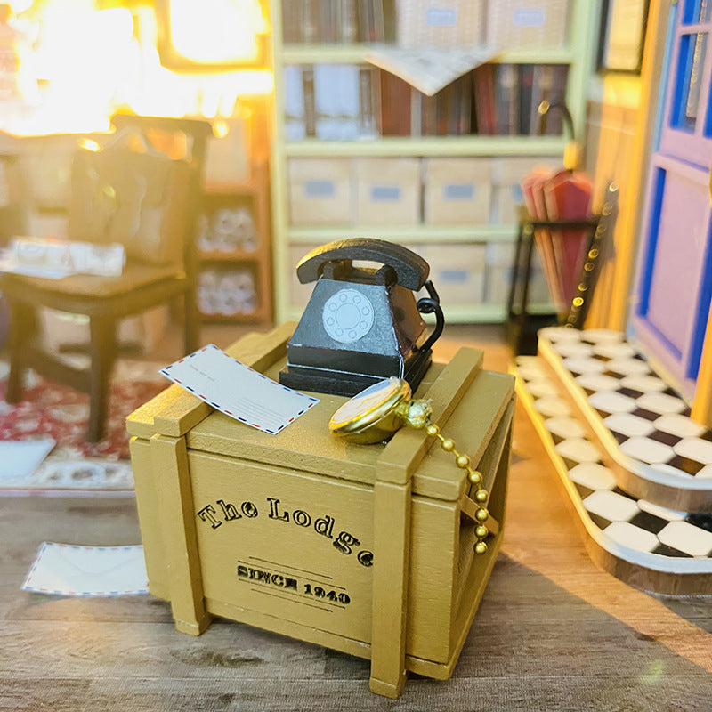 Close-up of a vintage telephone on a wooden crate in a detailed miniature dollhouse scene.