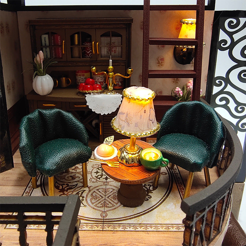 Cozy living room setup in a DIY dollhouse kit, featuring elegant green chairs and a charming lamp.