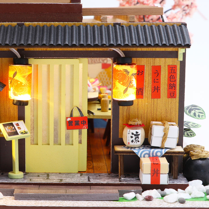 Sakura Sushi House DIY dollhouse kit with illuminated lanterns and miniature sushi decor, ideal for craft enthusiasts.