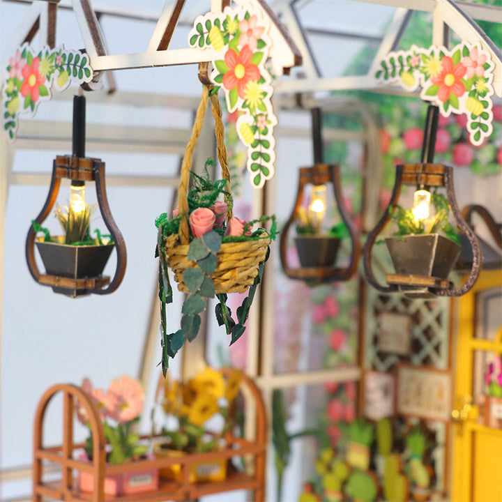Detailed view of illuminated lanterns and floral decorations in a DIY Book Nook Kit, featuring a charming garden aesthetic.
