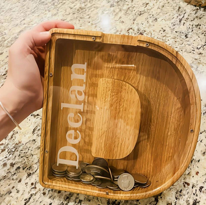 Personalized wooden piggy bank with coins, featuring child's name 'Declan' for teaching money savings.