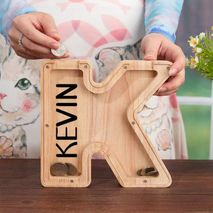 Personalized wooden letter piggy bank for kids, featuring the letter 'K' and name 'Kevin', designed for teaching savings.