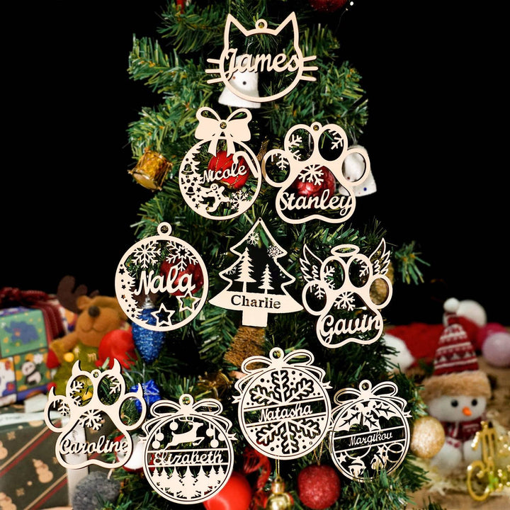 Personalized wooden paw angel wings ornaments for pets hanging on a Christmas tree, featuring names and festive designs.