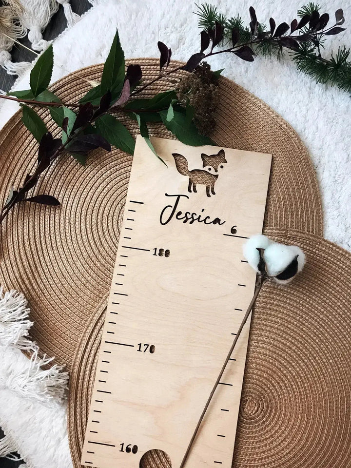 Personalized wooden height ruler featuring a fox design, measuring child's growth, surrounded by natural decor.