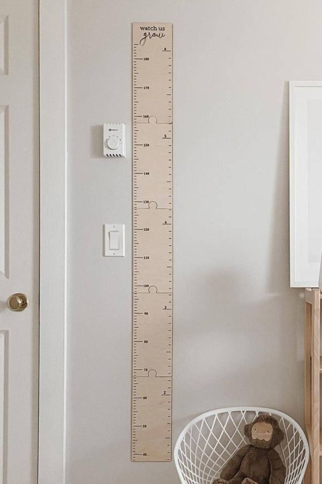 Personalized wooden growth chart ruler on wall for kids' room decor, measuring height with clear scales.