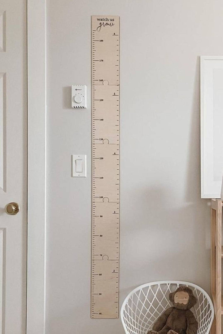 Personalized wooden growth chart ruler on wall for kids' room decor, measuring height with clear scales.