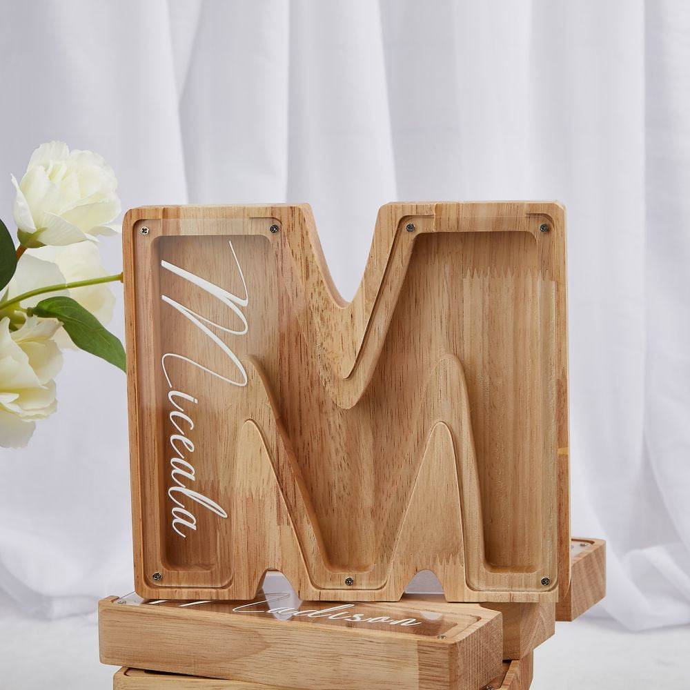 Personalized wooden letter 'M' piggy bank for kids, designed to teach financial awareness.
