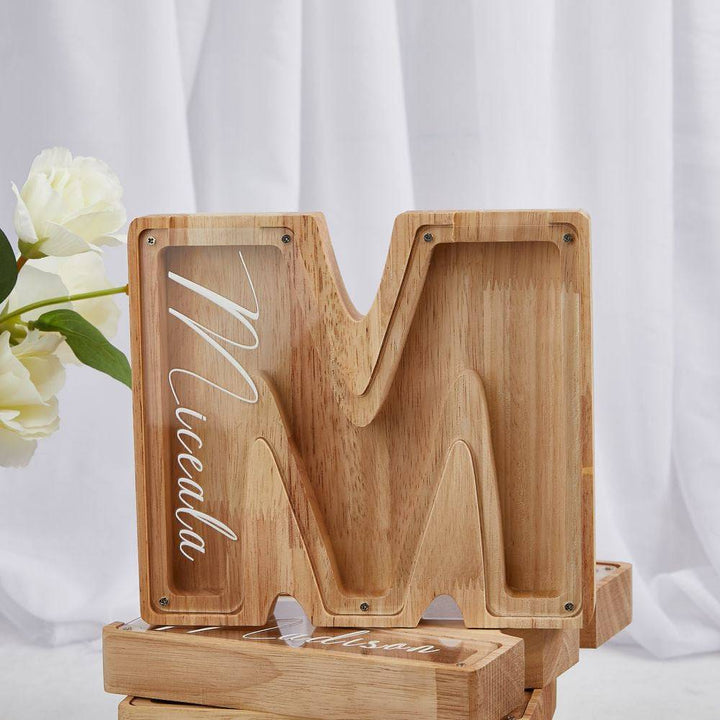 Personalized wooden letter 'M' piggy bank for kids, designed to teach financial awareness.