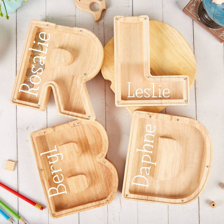 Personalized wooden letter trays with names Rosalie, Leslie, Beryl, and Daphne on a light wooden background.
