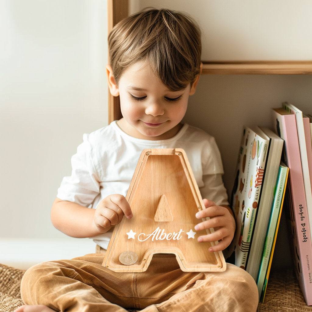 Smiling boy holding a custom wooden letter 'A' piggy bank, fostering early financial awareness.