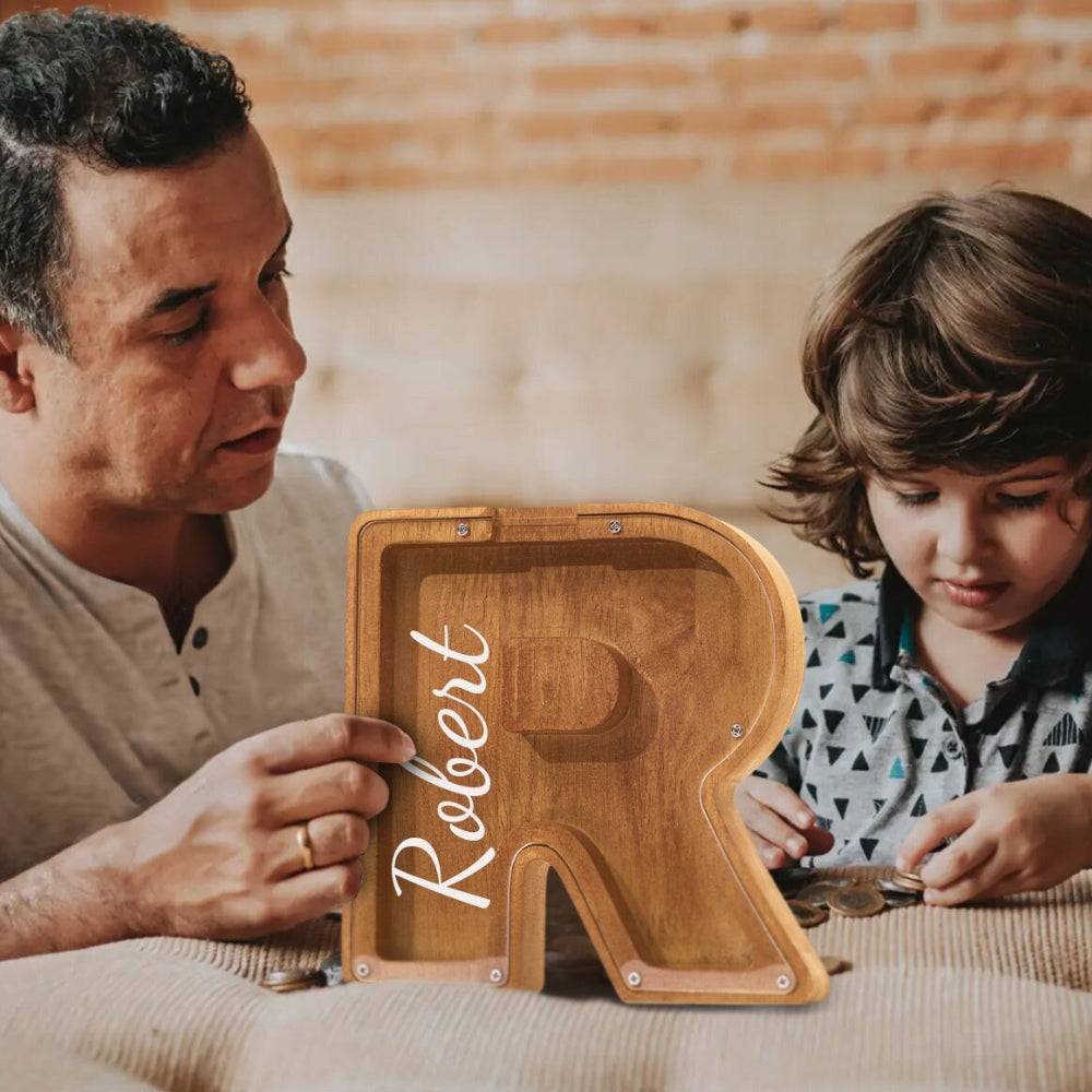 Father and son enjoying a personalized wooden letter piggy bank, teaching financial awareness with fun.