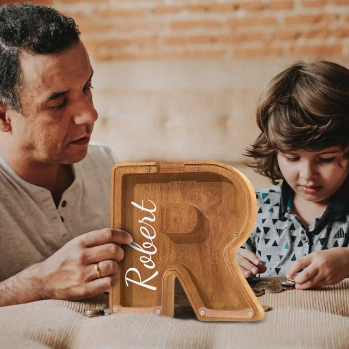Father and son enjoying a personalized wooden letter piggy bank, teaching financial awareness with fun.