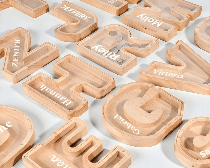 Personalized wooden letter piggy banks for kids showcasing various names on a light background.
