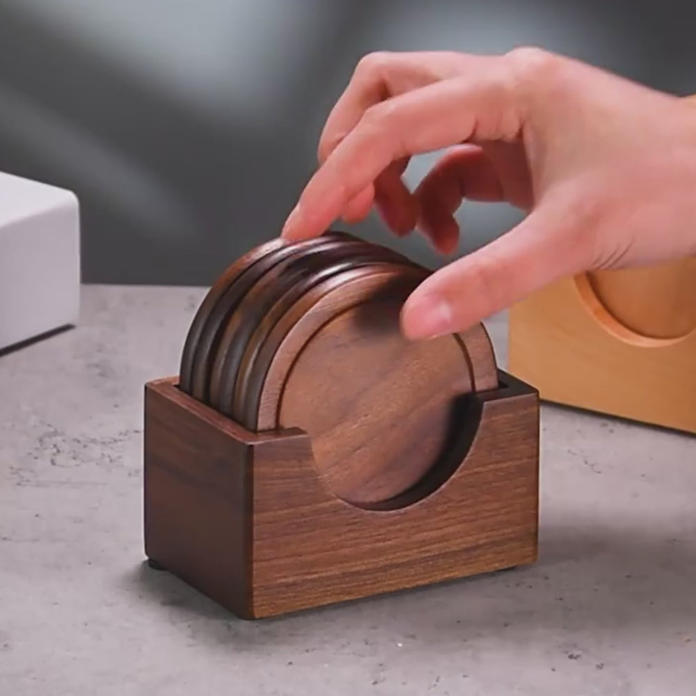 Hand reaching for minimalist walnut wooden coasters in a stylish holder on a tabletop.