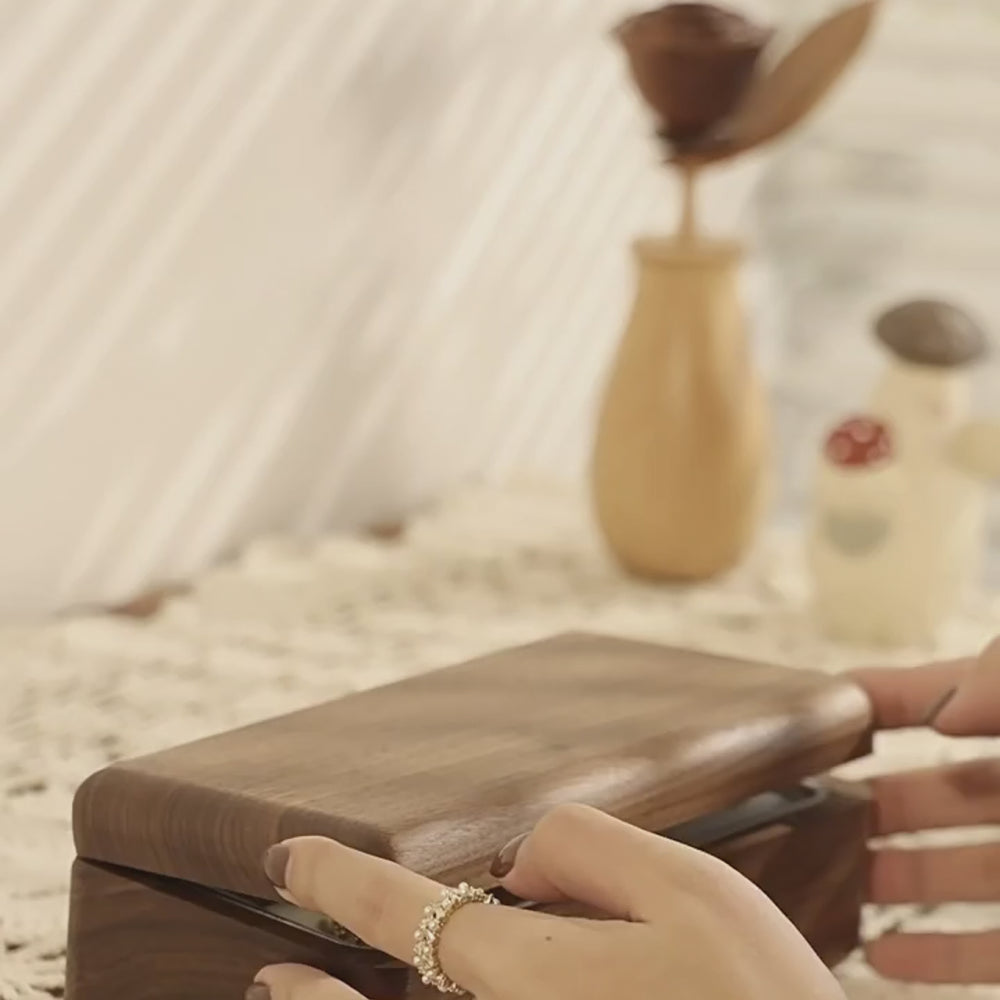 Elegant wooden double-layer jewelry box being opened, showcasing natural wood grain on a decorative table.