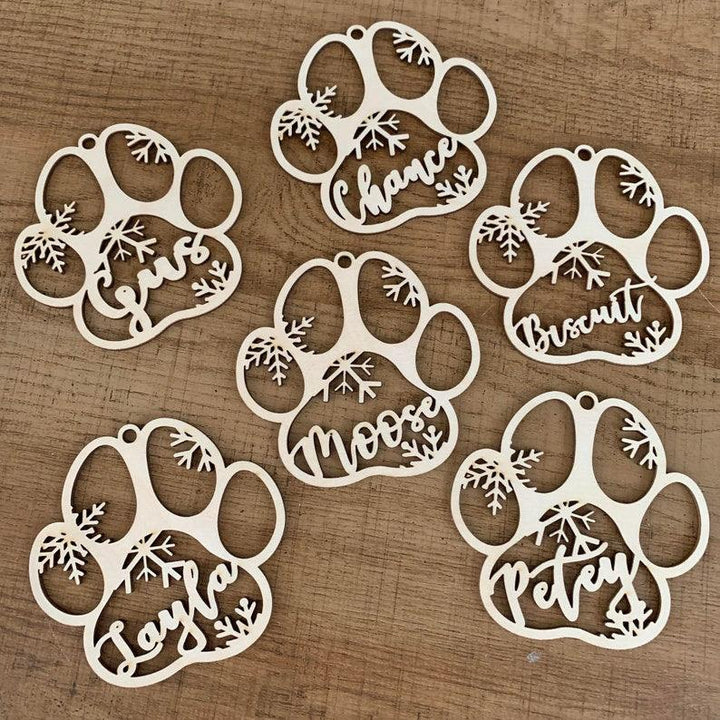 Personalized wooden paw print ornaments with names for pets, perfect for holiday decorations and crafting.