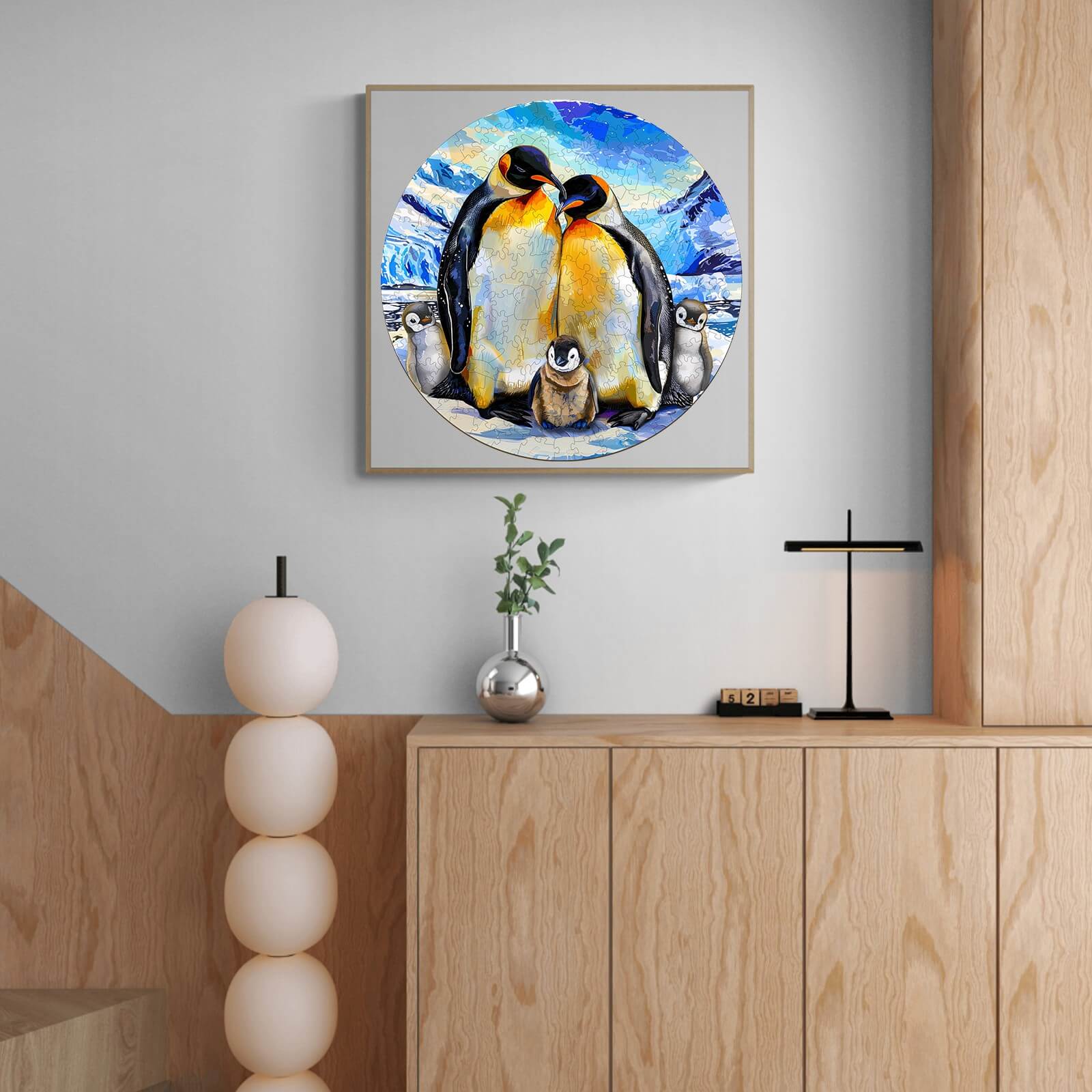 Vibrant painting of a penguin family displayed on a wooden wall, showcasing two adult penguins and a chick.