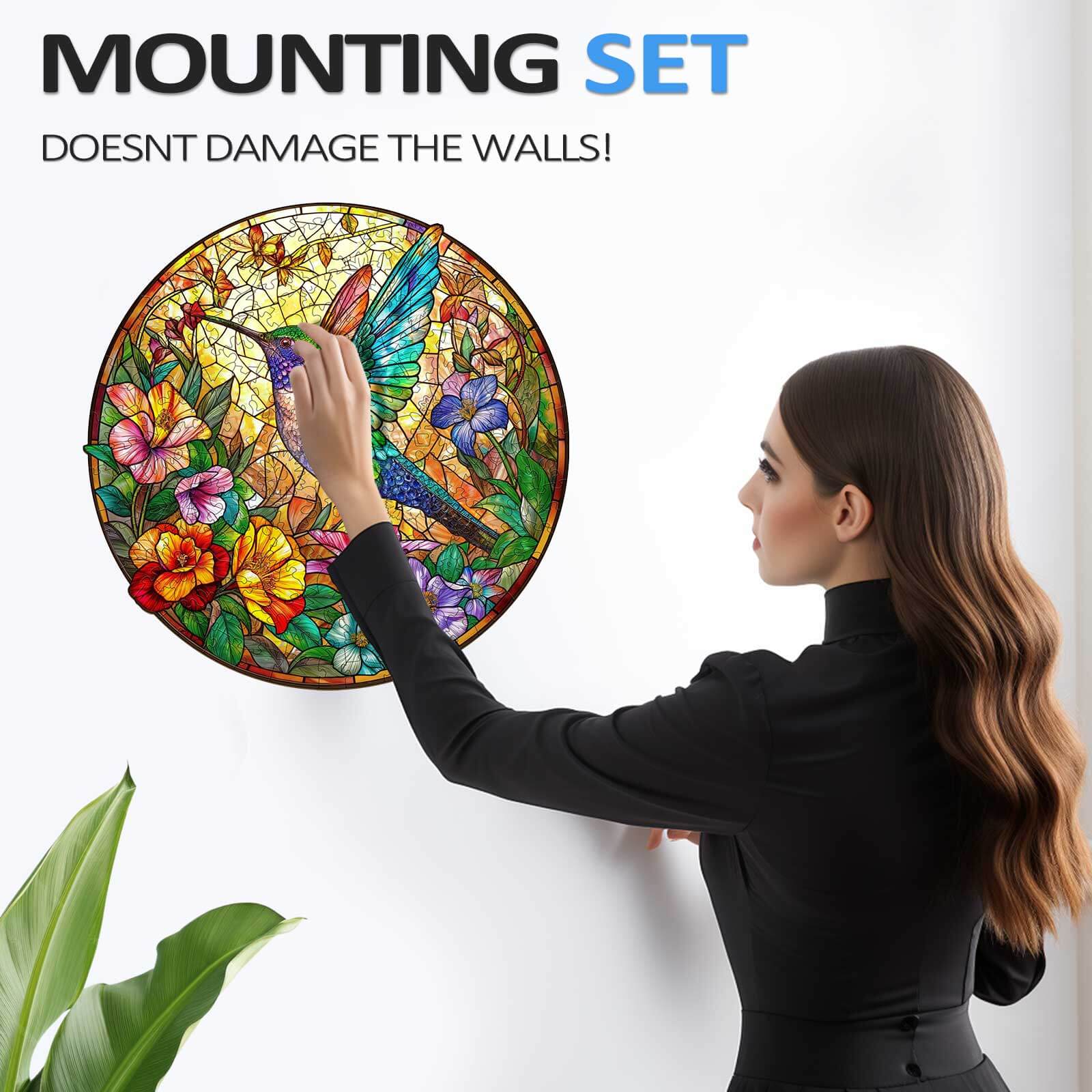 Woman showcasing a stained glass hummingbird jigsaw puzzle using a wall mount set that doesn't damage walls.