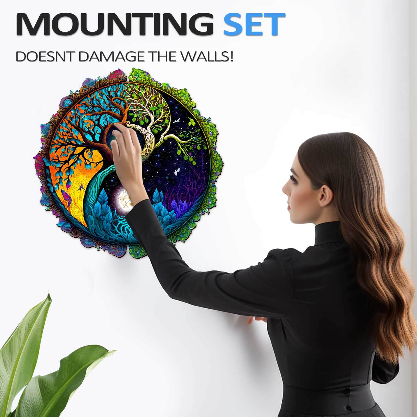 Woman using a non-damaging mounting set to display a colorful Yin Yang and Tree of Life puzzle on the wall.