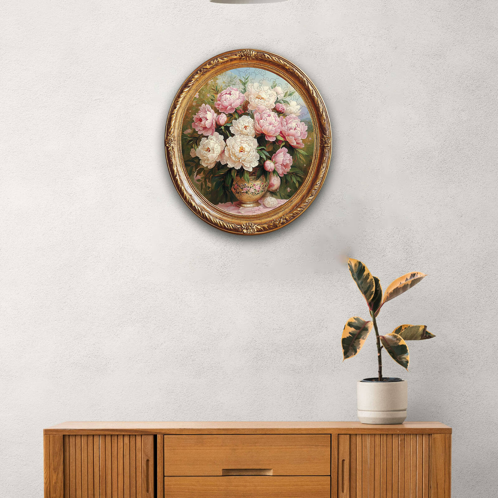 Elegant round floral artwork featuring pink and white flowers in a vase, beautifully displayed on a wall above a wooden cabinet.