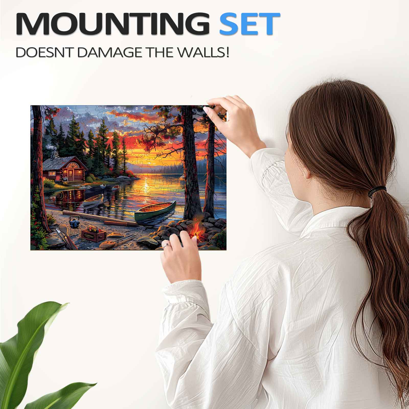 A woman hangs a beautiful sunset lake painting using a mounting set that won't damage walls.