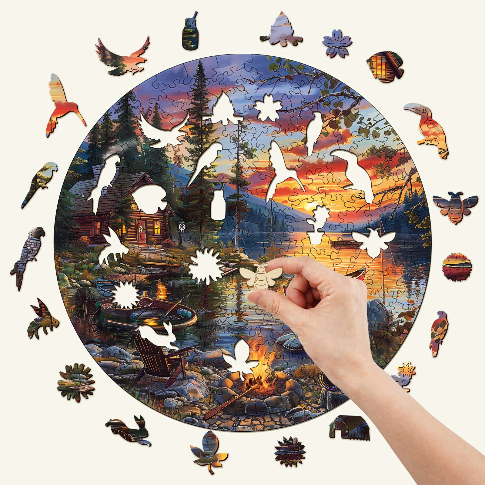 Hand placing a piece in the Canoe Lake-2 wooden jigsaw puzzle, featuring a scenic lakeside sunset.