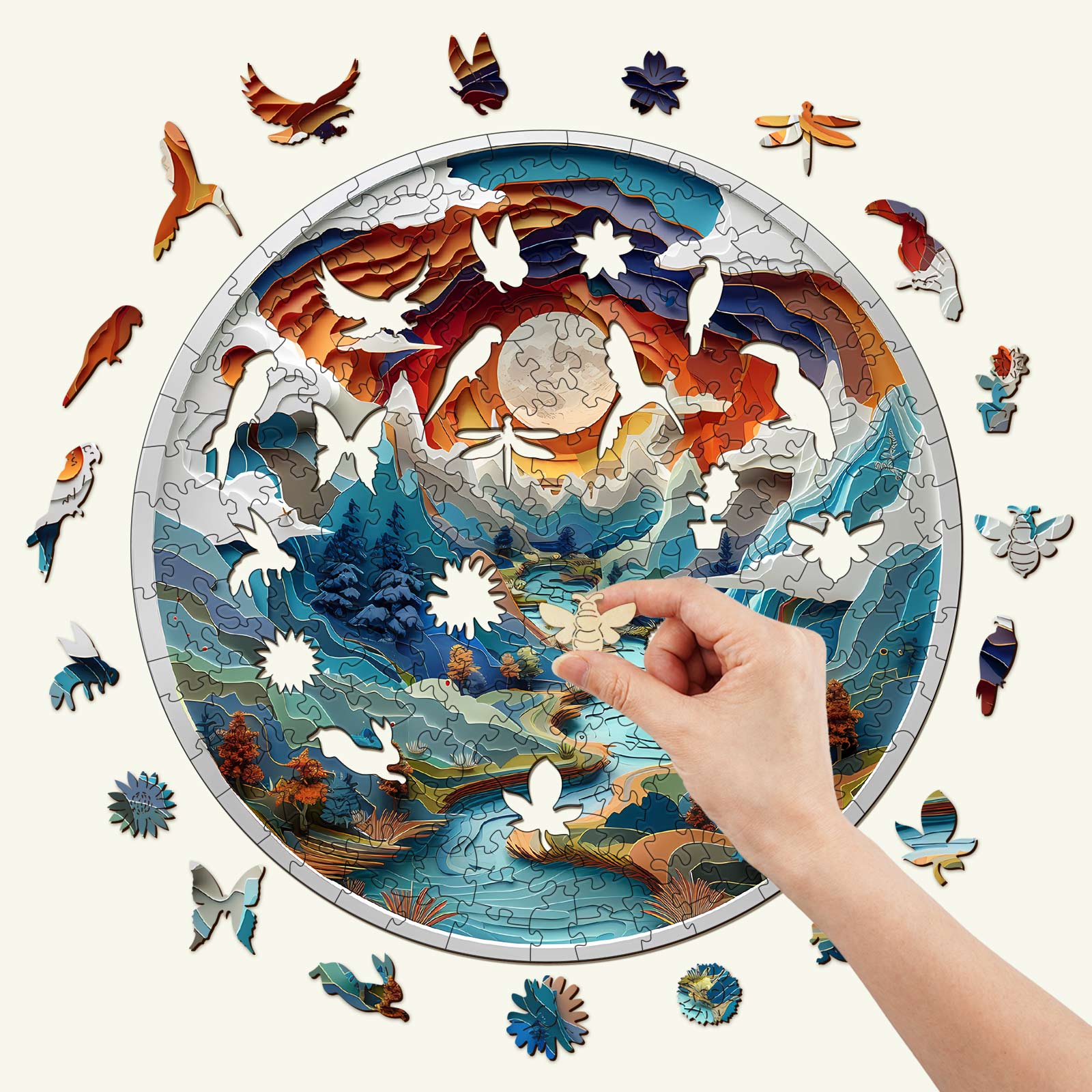 Person assembling a colorful 3D wooden jigsaw puzzle depicting a cave scene with wildlife and a river.