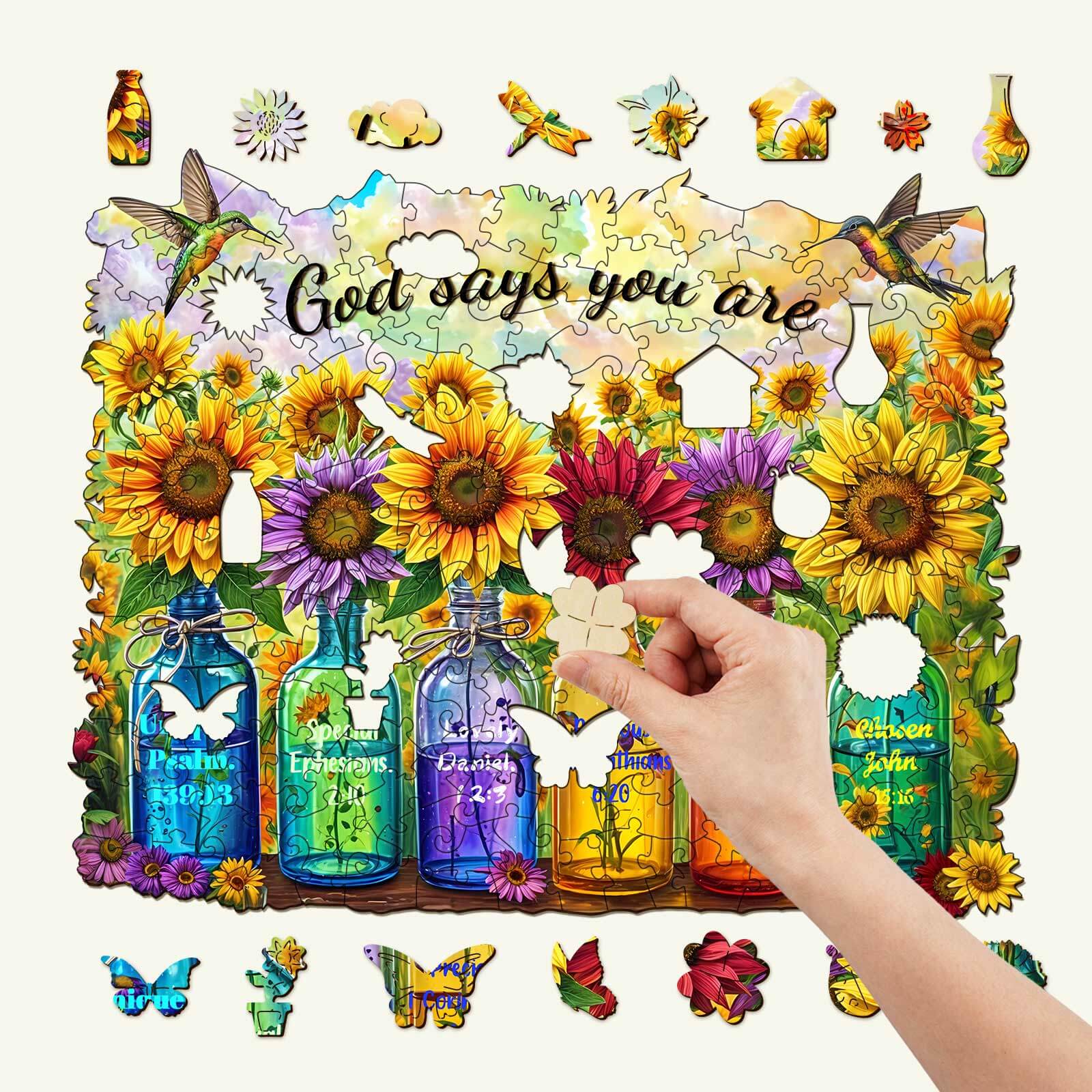 Hand placing a piece in the God Says You Are wooden jigsaw puzzle featuring colorful sunflowers and butterflies.