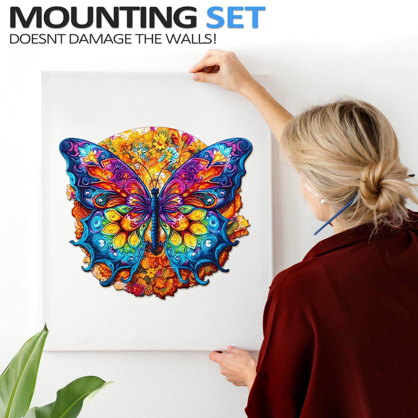 Person mounting a colorful butterfly art piece on the wall with a damage-free mounting set.