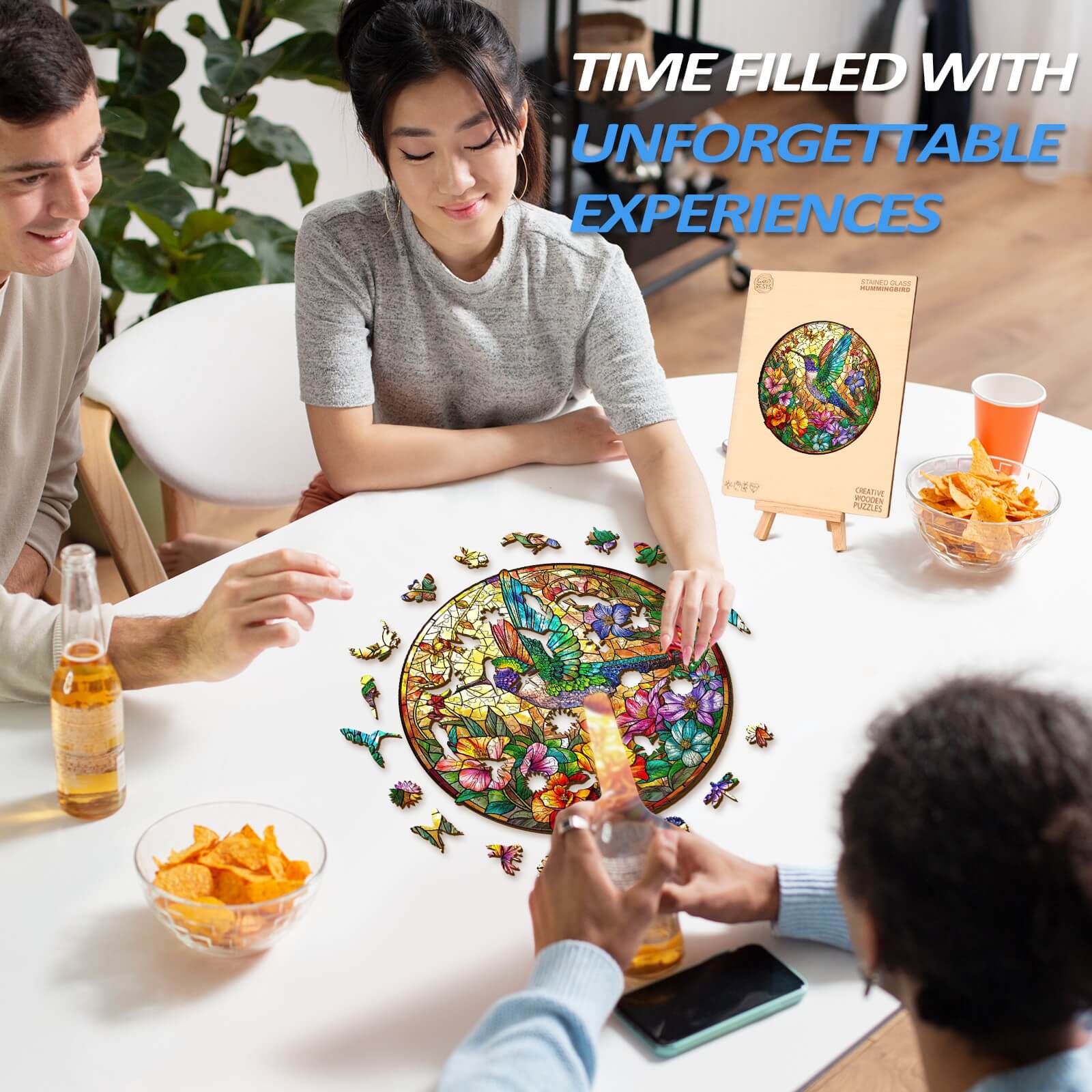 Group of friends enjoying a Stained Glass Hummingbird wooden jigsaw puzzle at a table, filled with snacks and drinks.