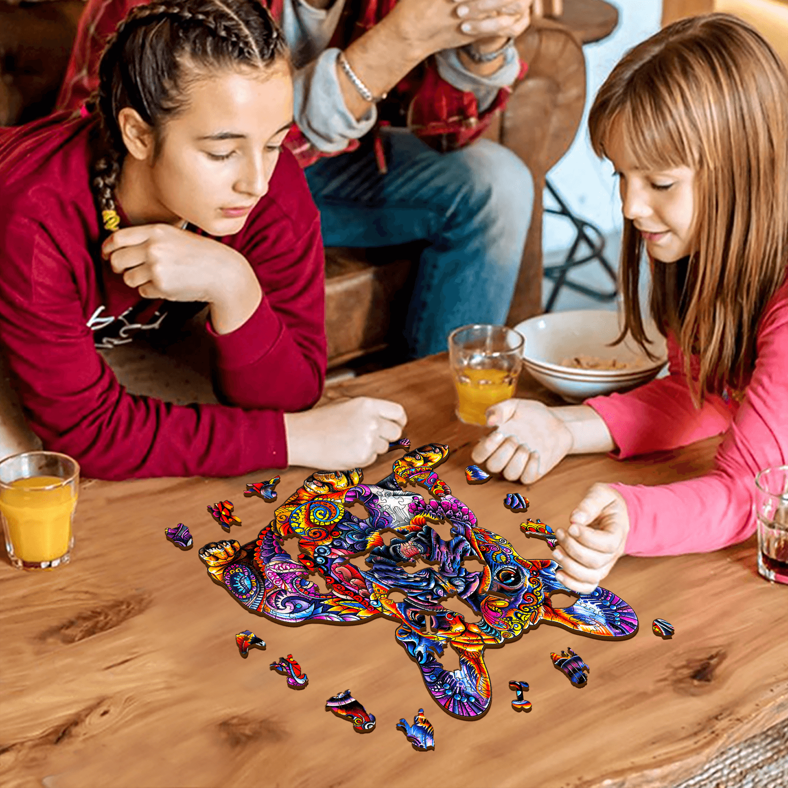 Two girls working together on a colorful French Bulldog wooden jigsaw puzzle on a wooden table.