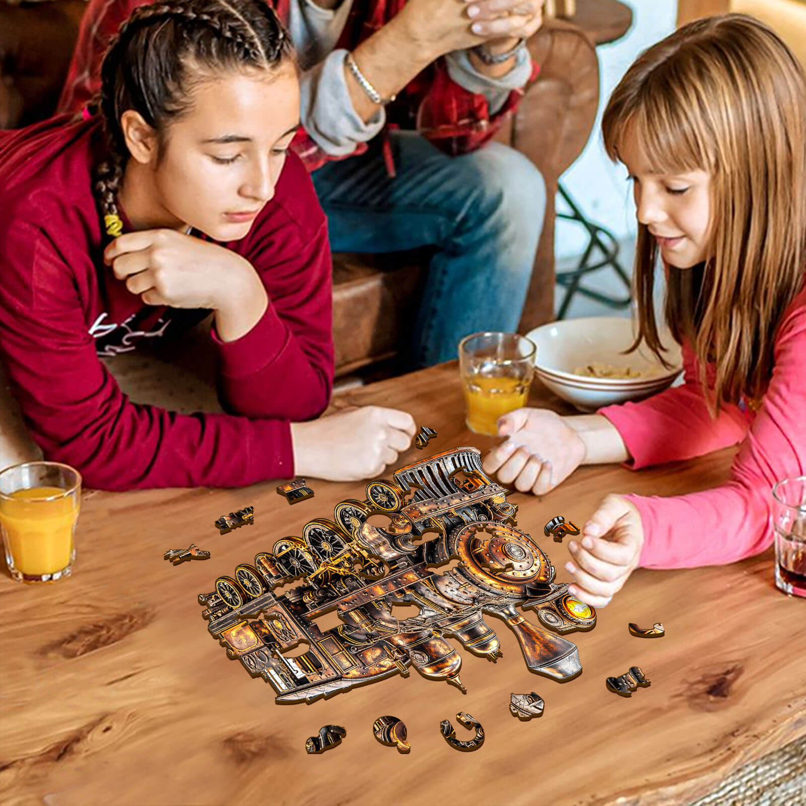 Two girls assembling a 3D Mechanical Steam Train Wooden Jigsaw Puzzle on a table surrounded by drinks.
