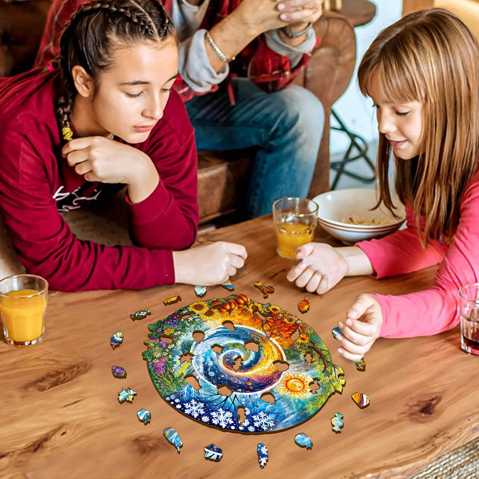 Two girls focused on solving the Seasons of Life wooden jigsaw puzzle surrounded by colorful pieces.