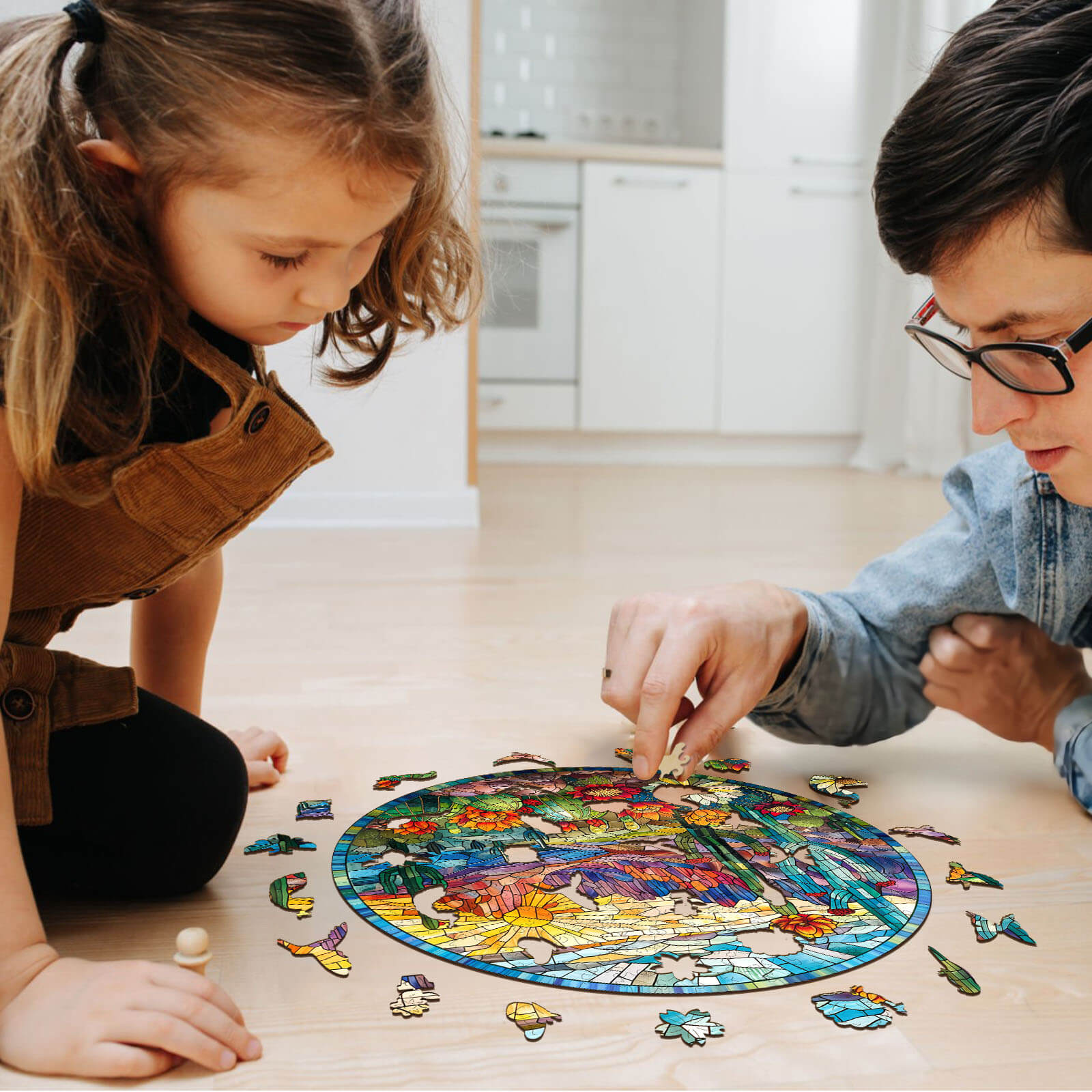 Adult and child assembling a colorful stained glass cactus wooden jigsaw puzzle on a floor.