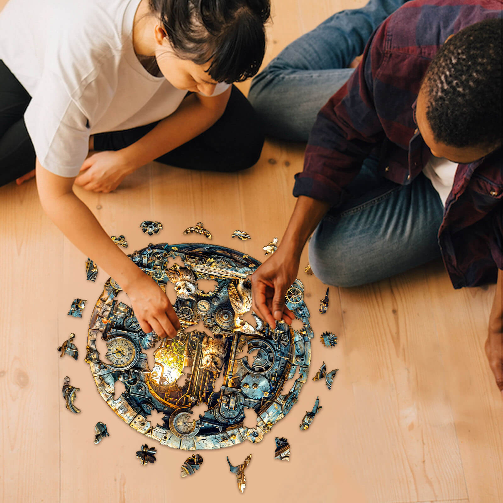Two people assembling a Steampunk Owl wooden jigsaw puzzle on a wooden floor, enhancing focus and problem-solving skills.
