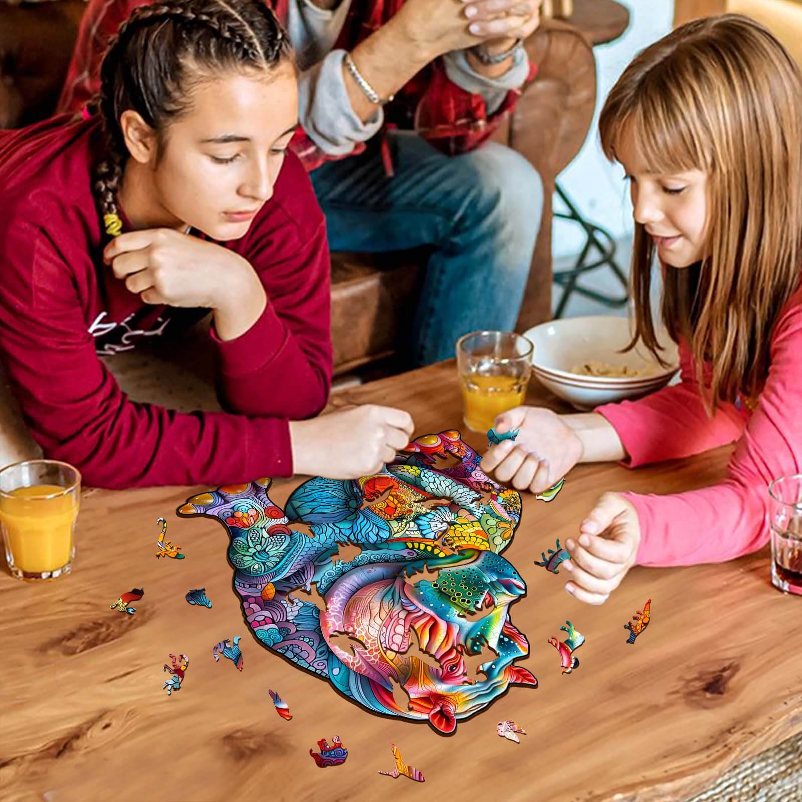 Two girls enjoying a colorful hippopotamus wooden jigsaw puzzle on a table, perfect for mind games and family fun.