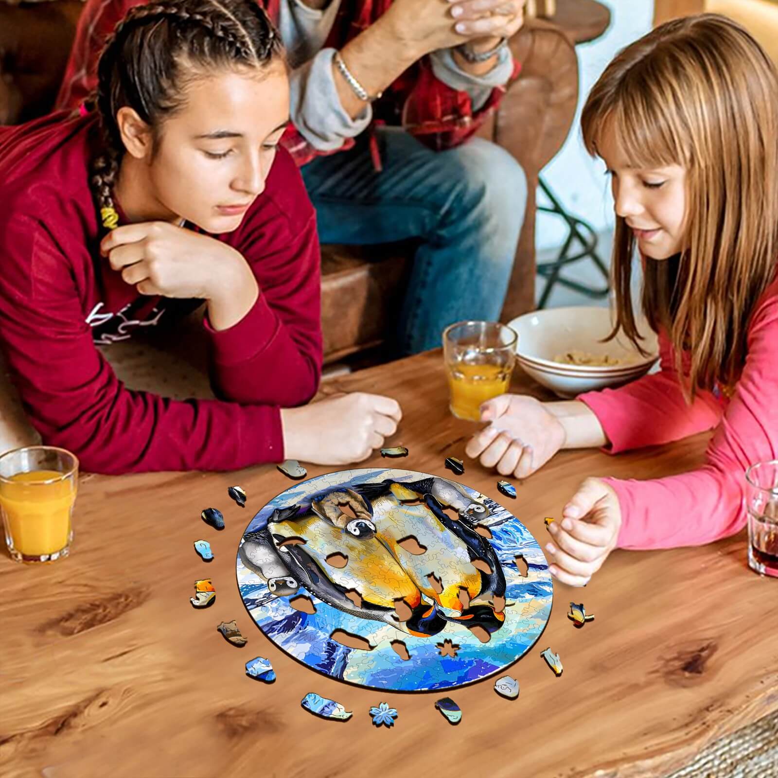 Two children solving a Penguin family-2 wooden jigsaw puzzle on a wooden table, enjoying a fun family activity.